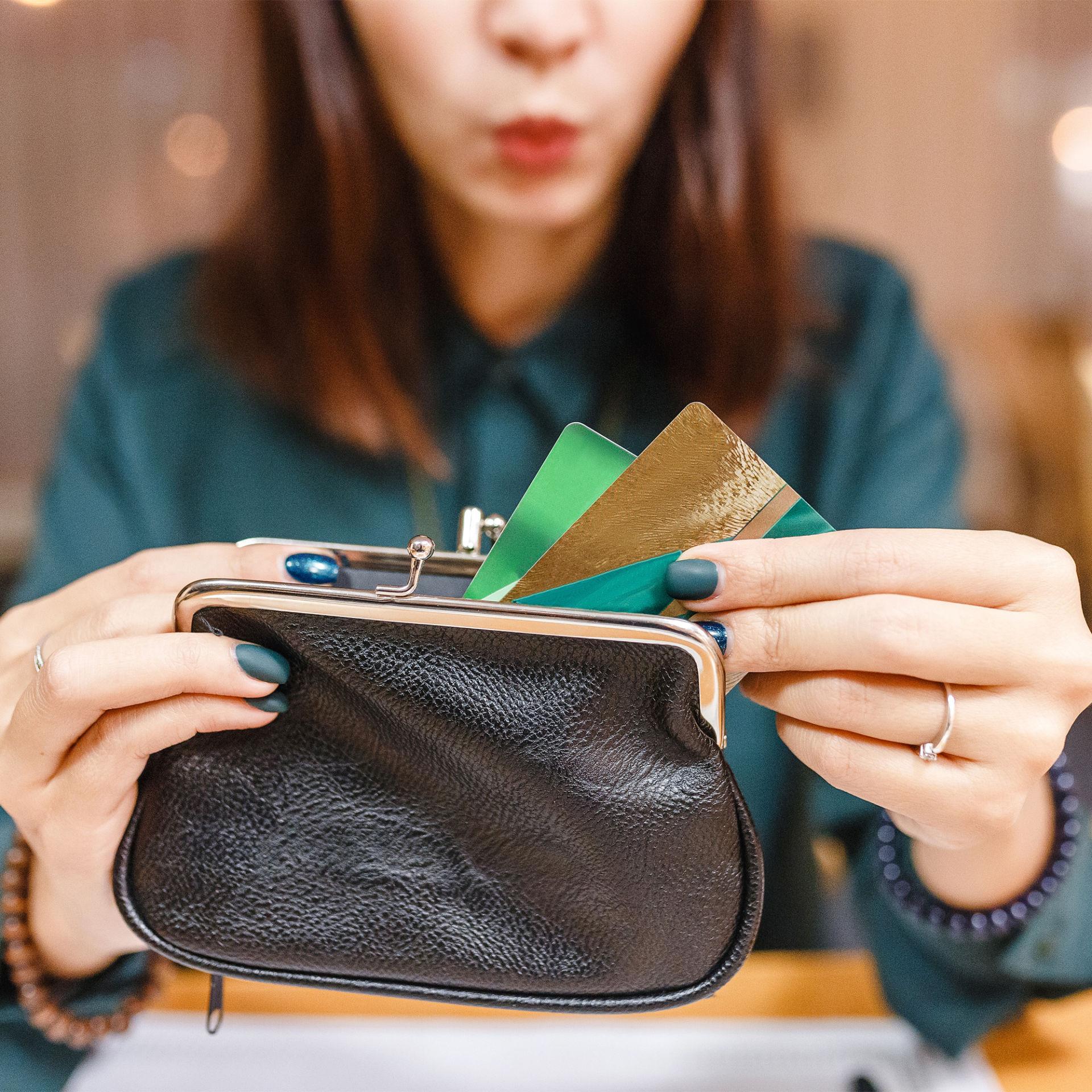 一个女人从钱包里拿出几张卡，想知道她是否应该用信用卡来支付所有的费用